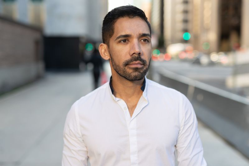 young hispanic man walking in the city