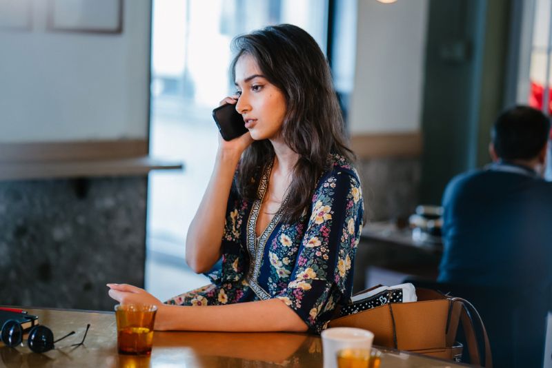 indian american woman making a phone call in a coffee shop