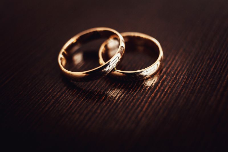 Two gold wedding rings on a wood table