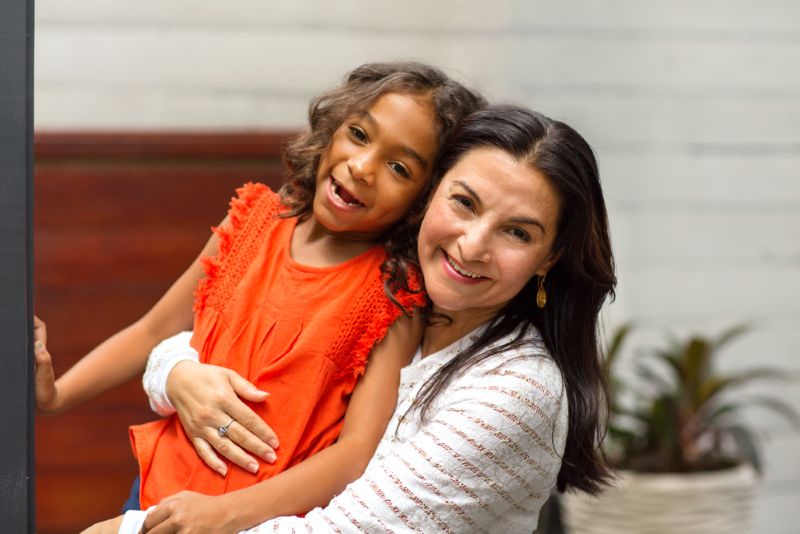 Immigrant woman holding her smiling daughter